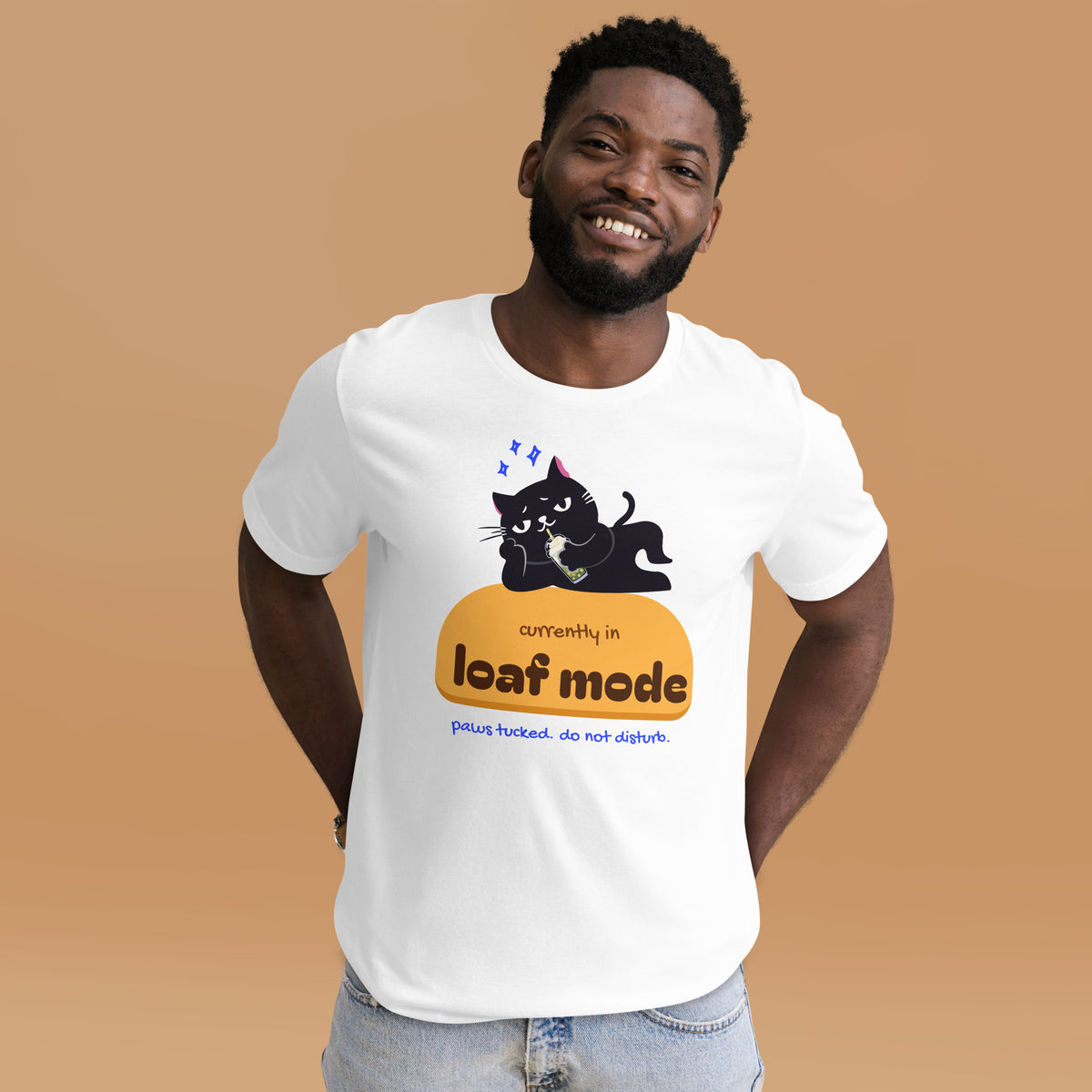 Man wearing a white unisex t-shirt with a black cat sipping boba on an orange loaf and the words “currently in loaf mode”