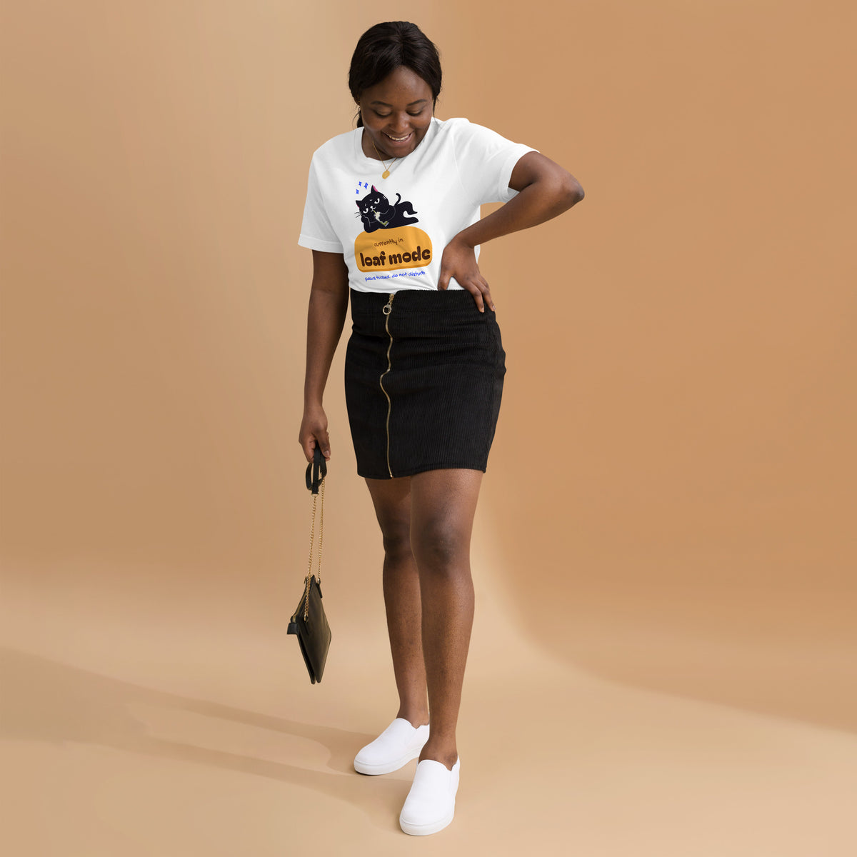 Woman wearing a white unisex t-shirt with a black cat sipping boba on an orange loaf and the words “currently in loaf mode”